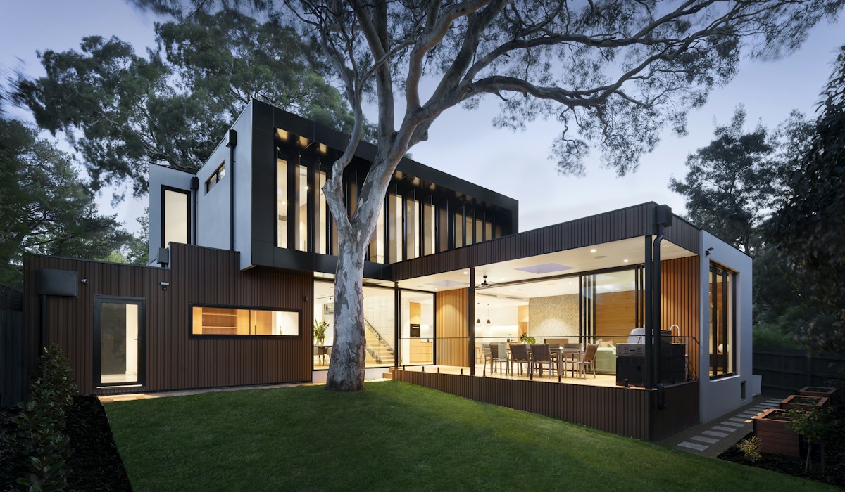 Residência contemporânea iluminada à noite com acabamento premium e paisagismo arquitetônico