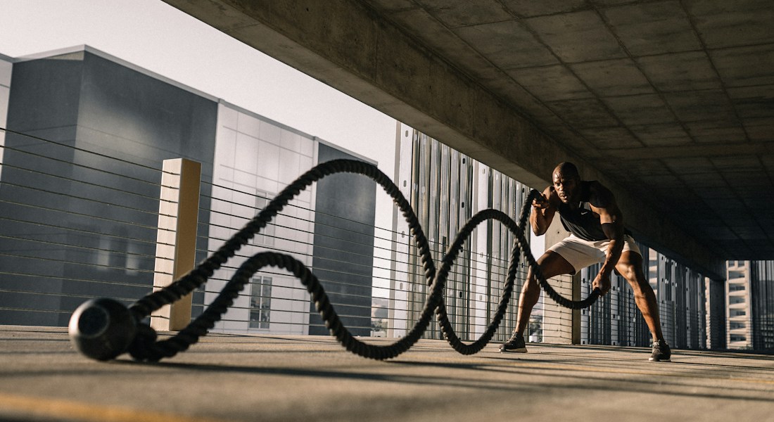 Atleta em exercício dinâmico de condicionamento físico demonstrando alto nível de engajamento e acompanhamento técnico