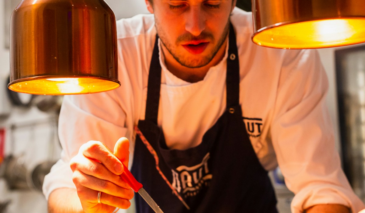 Chef e equipe de cozinha trabalhando na montagem padronizada dos pratos com foco em eficiência