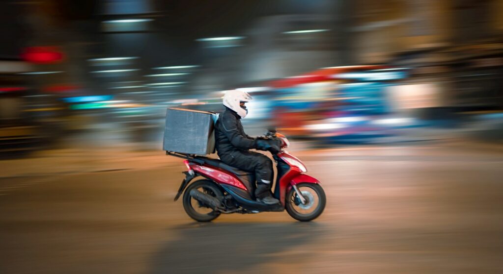 Profissional de entrega segurando pacote de delivery gastronômico com pontualidade