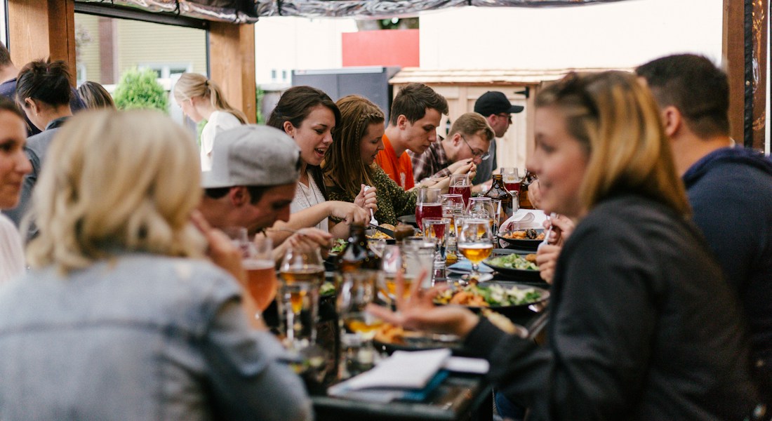 Grupo de clientes e amigos compartilhando refeição em restaurante com experiência acolhedora