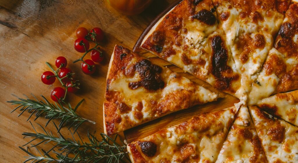 Pizza artesanal de fermentação natural com queijo derretido e manjericão fresco saindo do forno