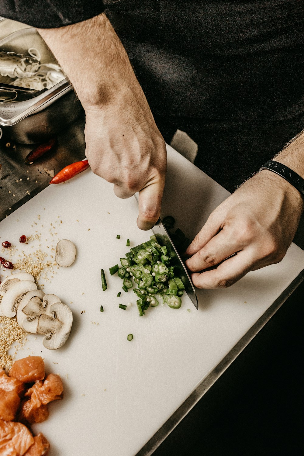 Chef profissional com jaleco branco empratando com pinça e precisão milimétrica em cozinha profissional